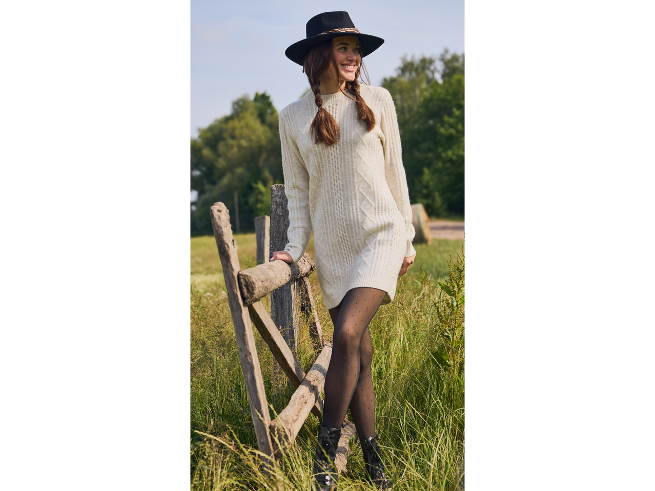 Woman in an esmara® ladies' jumper dress and hat, leaning on a wooden fence.