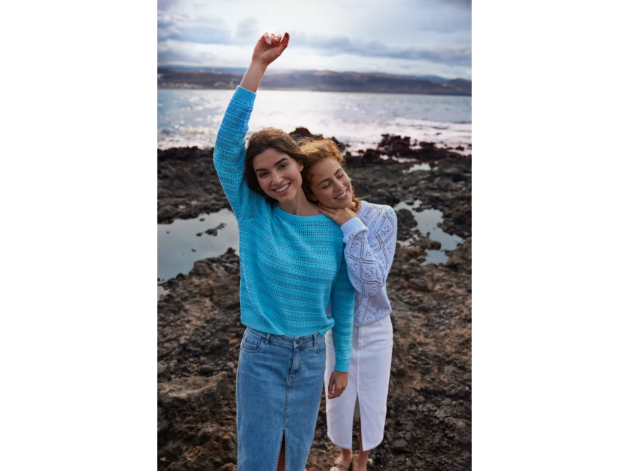 Duas mulheres com saias de ganga e camisolas de malha junto ao mar