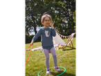 Menina com óculos brincando com hula hoop no jardim.