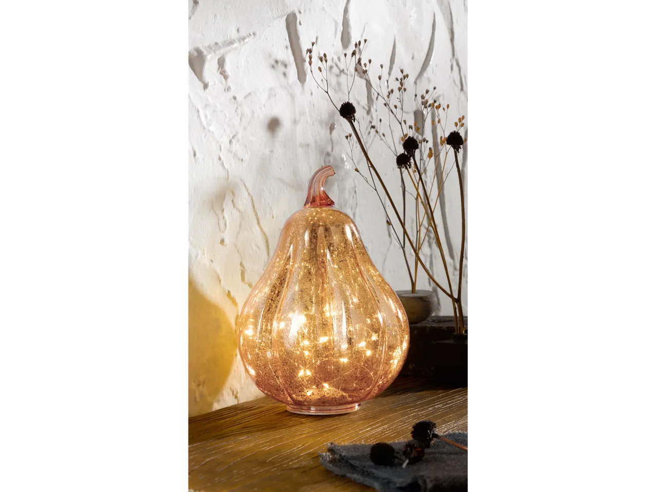 LIVARNO home Light-Up Decorative Pumpkin on a wooden surface with dried plants.