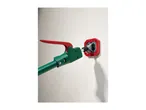 A green and red long-handled tool engaging with a red wall-mounted socket.