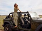 Női modell egy zöld Jeep Wranglerben, virágos midi szoknyában.