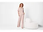 Woman in light pink pajamas with a white armchair.
