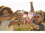 Friends toasting with glitter tumblers at a festival.
