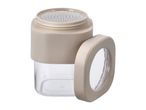 Beige and clear spice shaker with a perforated lid and an open side cap.