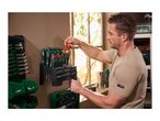 Man organizing a large set of screwdrivers and bits on a wall-mounted tool holder.