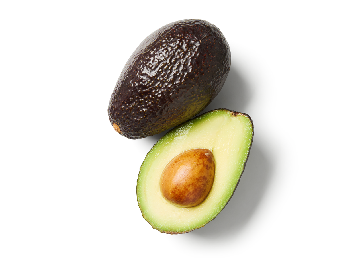 Avocado Hass întreg și unul tăiat pe jumătate cu sâmburele