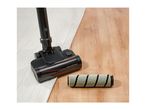 Vacuum cleaner head on a rug next to an interchangeable roller brush on a wooden floor.