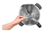 Hand holding a blender blade inside a stainless steel mixing bowl with volume markings.