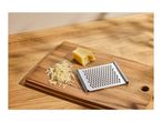 Grated cheese, a block of cheese, and a grater on a wooden cutting board.