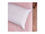A white pillow with gray piping on a pink sheet, with a wooden floor visible.