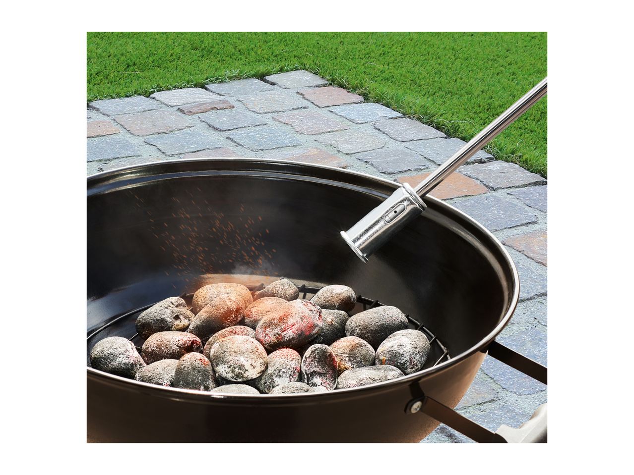 Barbecue with glowing charcoal briquettes being lit by a charcoal starter.