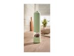 A green SilverCrest electric pepper grinder filled with peppercorns on a wooden counter.