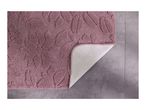 Pink floral bath mat with a non-slip backing, partially folded on a tiled floor.