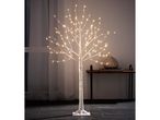Illuminated birch tree with warm white LED lights, standing on a dark floor next to a window.