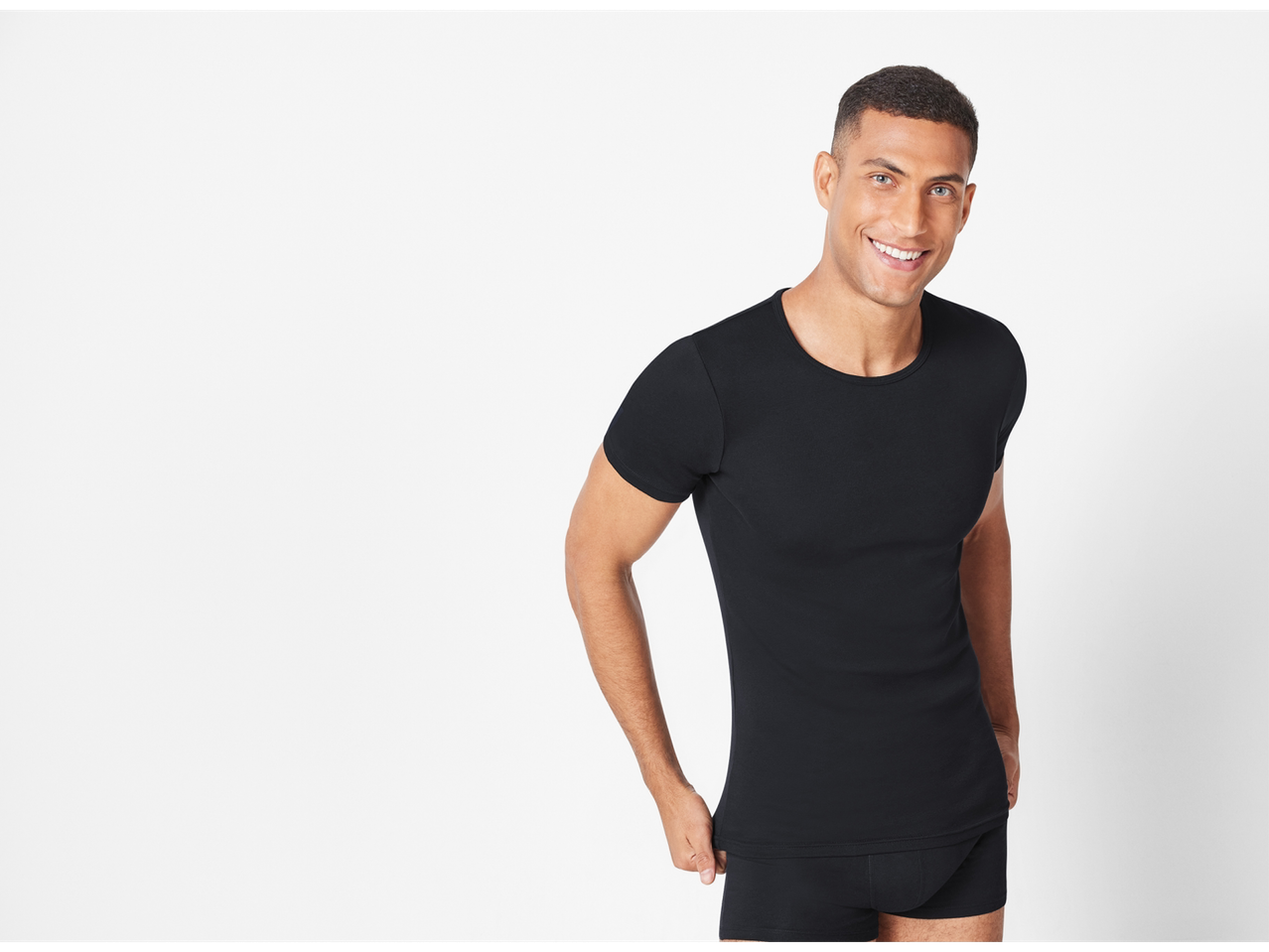 Smiling male model wearing a black t-shirt and underwear.