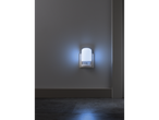 A white night light plugged into a wall outlet, emitting a soft blue glow onto the floor.