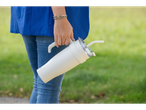 Woman holding a white tumbler with straw.