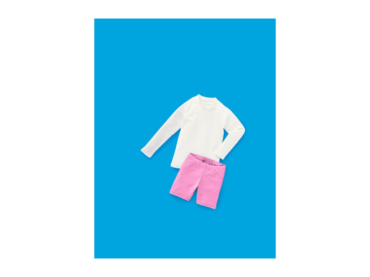 White long-sleeved top and pink shorts on a blue background.