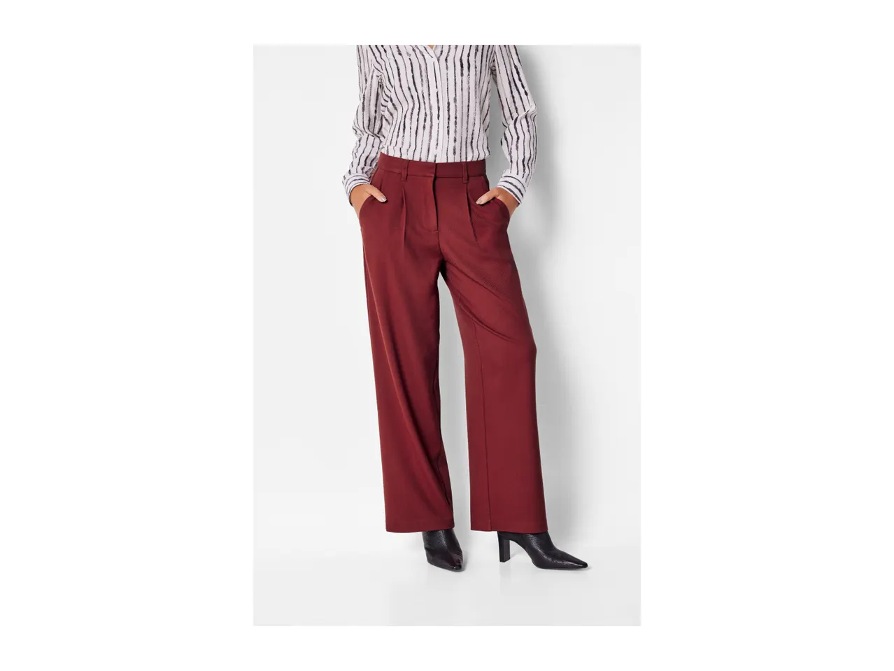 A person wearing a striped shirt, red wide-leg trousers, and black pointed-toe boots.