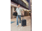 Homem de camisa às riscas e jeans, puxando uma mala ESMARA e carregando uma mala de viagem.