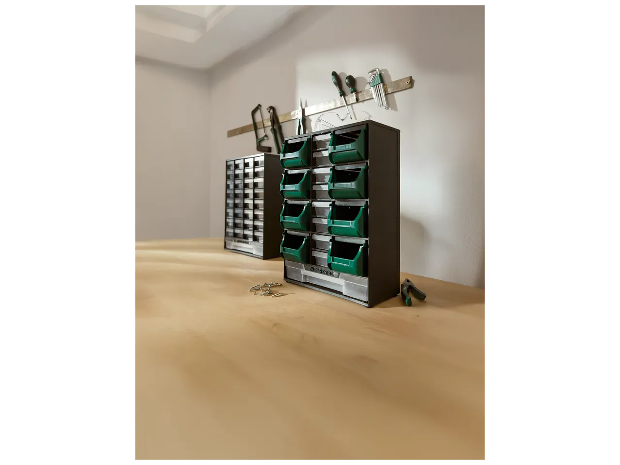 Organiseurs de rangement pour petites pièces et outils sur un établi en bois.