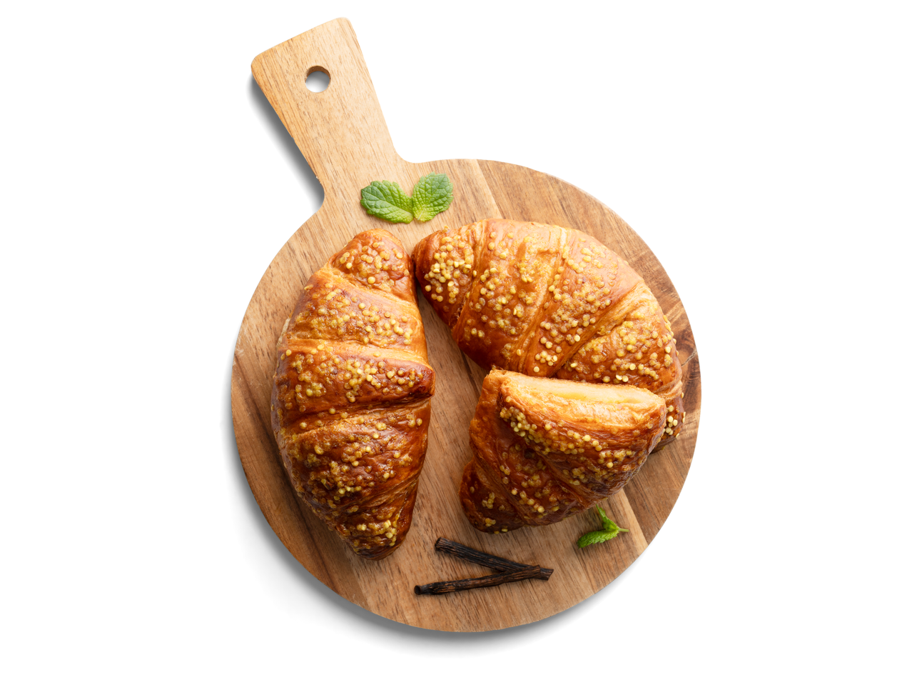 Két croissant egy fa vágódeszkán, menta levelekkel és vaníliarúddal.
