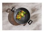 Overhead shot of a black speckled wok with cooked vegetables on a concrete surface.