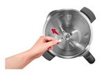 Hand removing the blade from a stainless steel blender bowl with measurement markings.