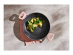 Overhead shot of a black speckled pan with pink handles, filled with cooked vegetables.