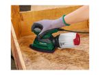 Hand holding an orbital sander on a wooden surface