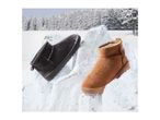Two winter boots, one brown and one black, on snow-covered rocks with a snowy forest background.