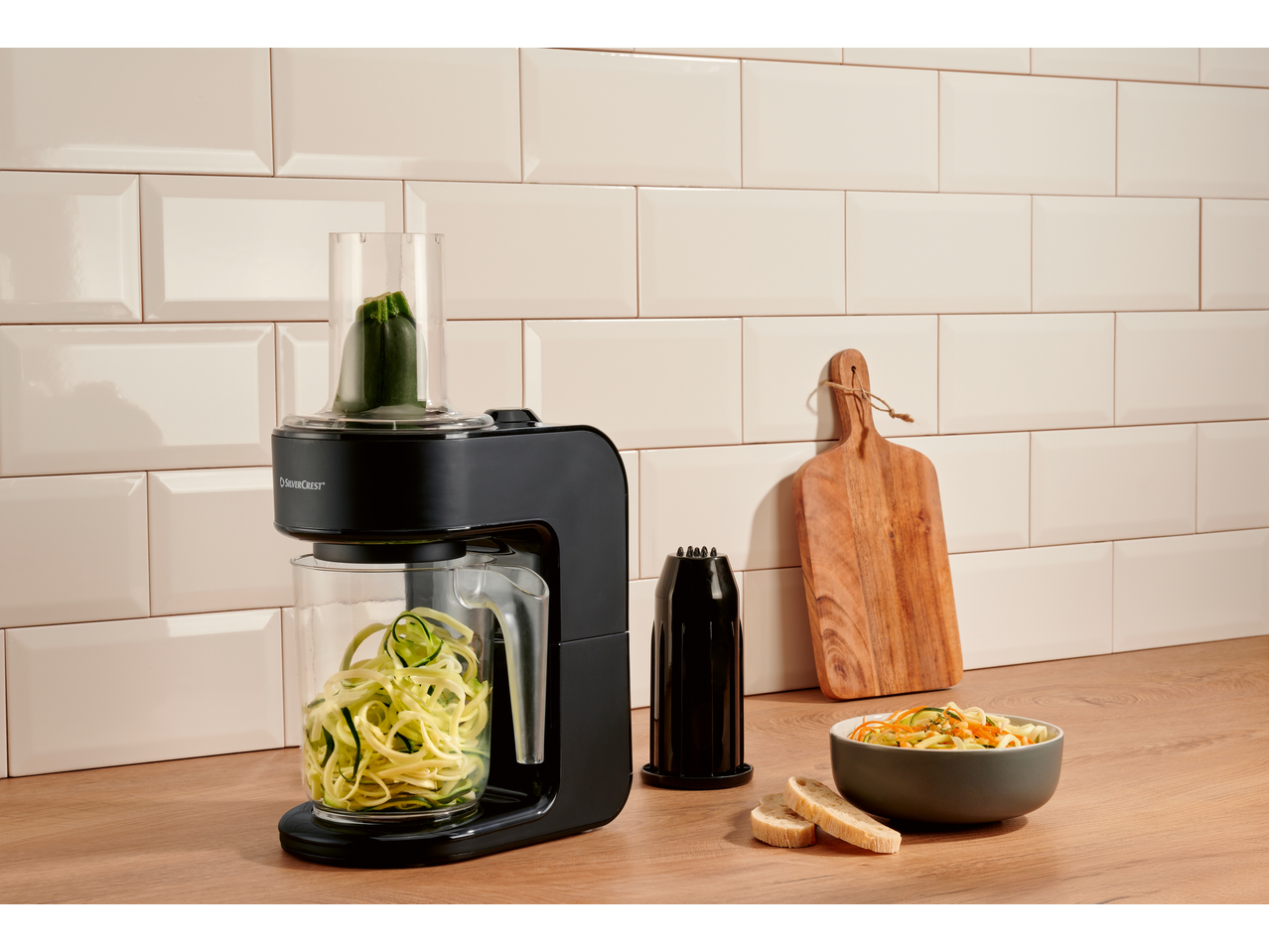 Spiralizator electric de legume SILVERCREST pe un blat de bucătărie cu dovlecei și un bol de salată.