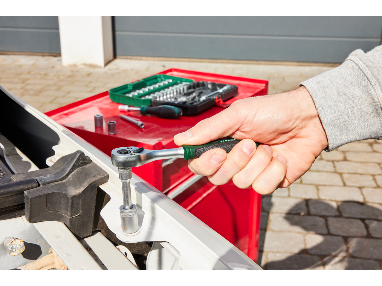 A mechanic uses a Parksider ratchet and tool set to repair a car.