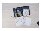 An art kit with pencils, paper, and a sharpener on a wooden table.