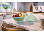 Fruit bowl with apples, grapes, and bananas, next to a mesh food cover in a modern kitchen.