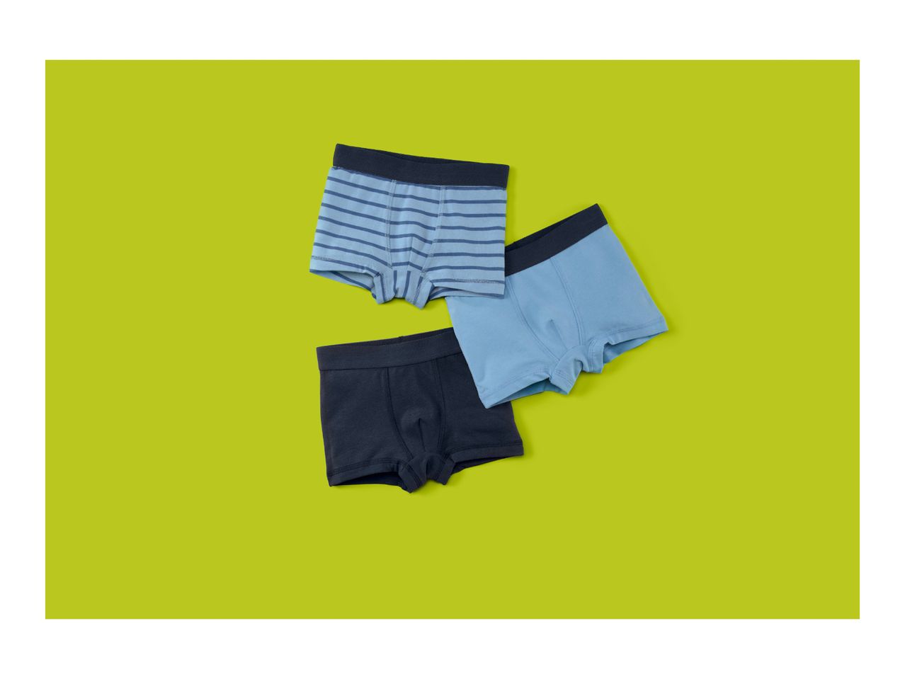 Three pairs of boys' boxer briefs in shades of blue, one striped, on a lime green background.