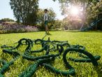 A green garden hose lies coiled on a lush lawn.