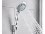 A chrome and white adjustable shower head sprays water against a tiled wall.