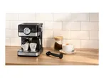 Espresso machine brewing coffee into two cups, with a jar of coffee and a cappuccino nearby.