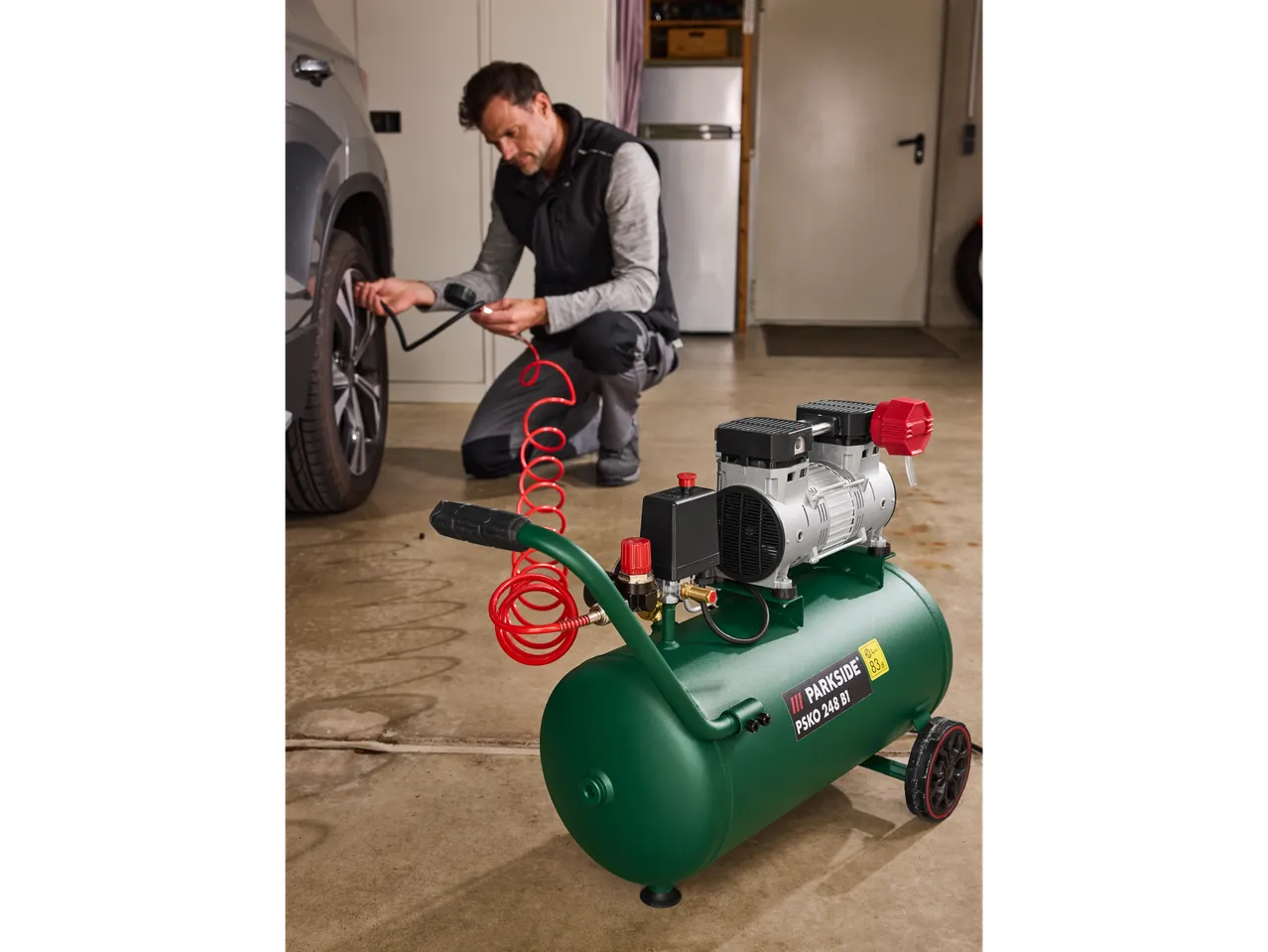 Man inflating car tire with a Parkside® Silent compressor PSKO 248.
