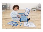 A child playing with a wooden activity desk, a puzzle, and coloring sheets on a wooden floor.