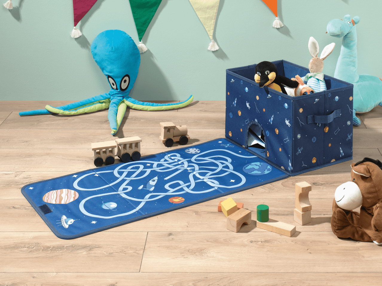 Spielzeug-Aufbewahrungsbox mit Weltraum-Design und passender Spielmatte auf Holzboden.