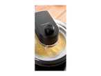 Ice cream maker with yellow ice cream mixture and a transparent measuring cup.