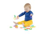 Happy baby in blue top and yellow pants playing with colorful linking rings.