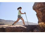 Woman in a light green t-shirt and grey shorts hiking with trekking poles.