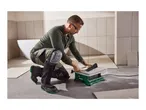 Man cutting a tile with a Parkside tile cutter, wearing safety glasses and knee pads.