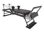 Black Pilates reformer machine with padded carriage, ropes, and foot bar.