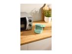 Microwave oven and a light green food container on a wooden kitchen counter.