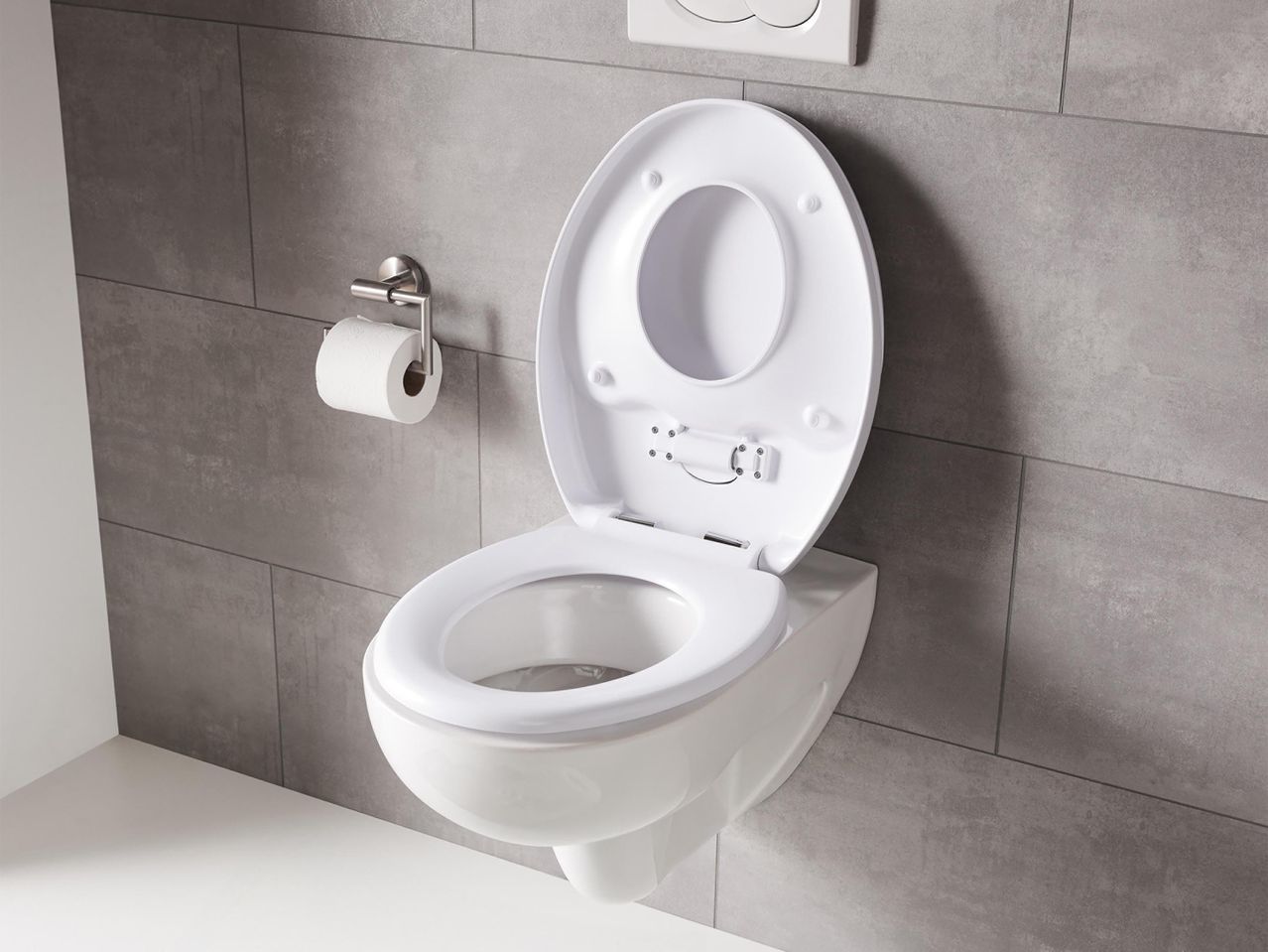Modern, falra szerelhető WC ülőke, nyitott fedéllel, szürke csempével.